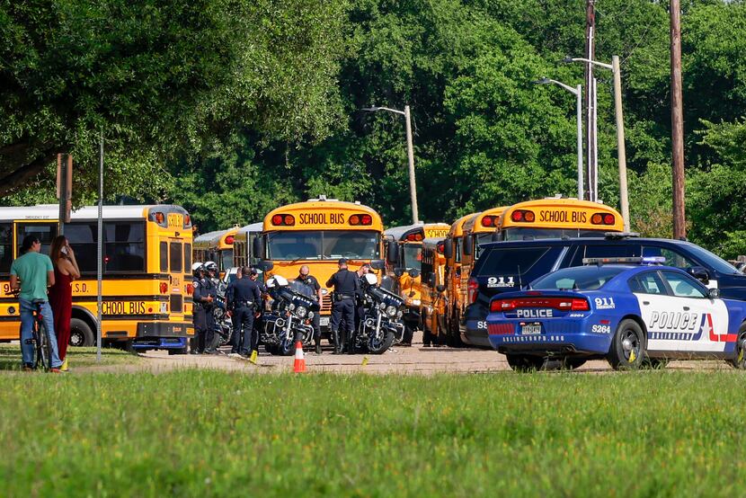 Several police motorcycles sit in front of several school buses after a shooting occurred...
