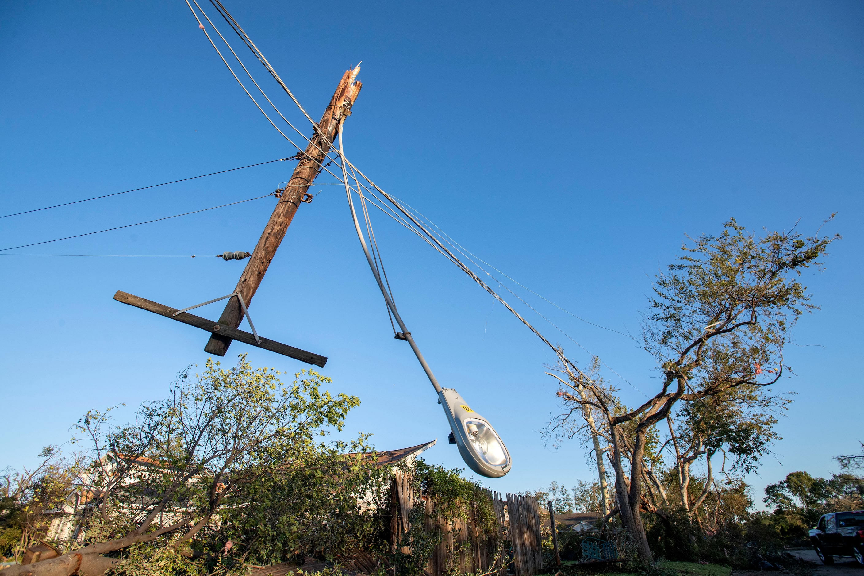 A broken utility pole hangs upside down on Coppedge Lane north of Walnut Hill after Sunday...