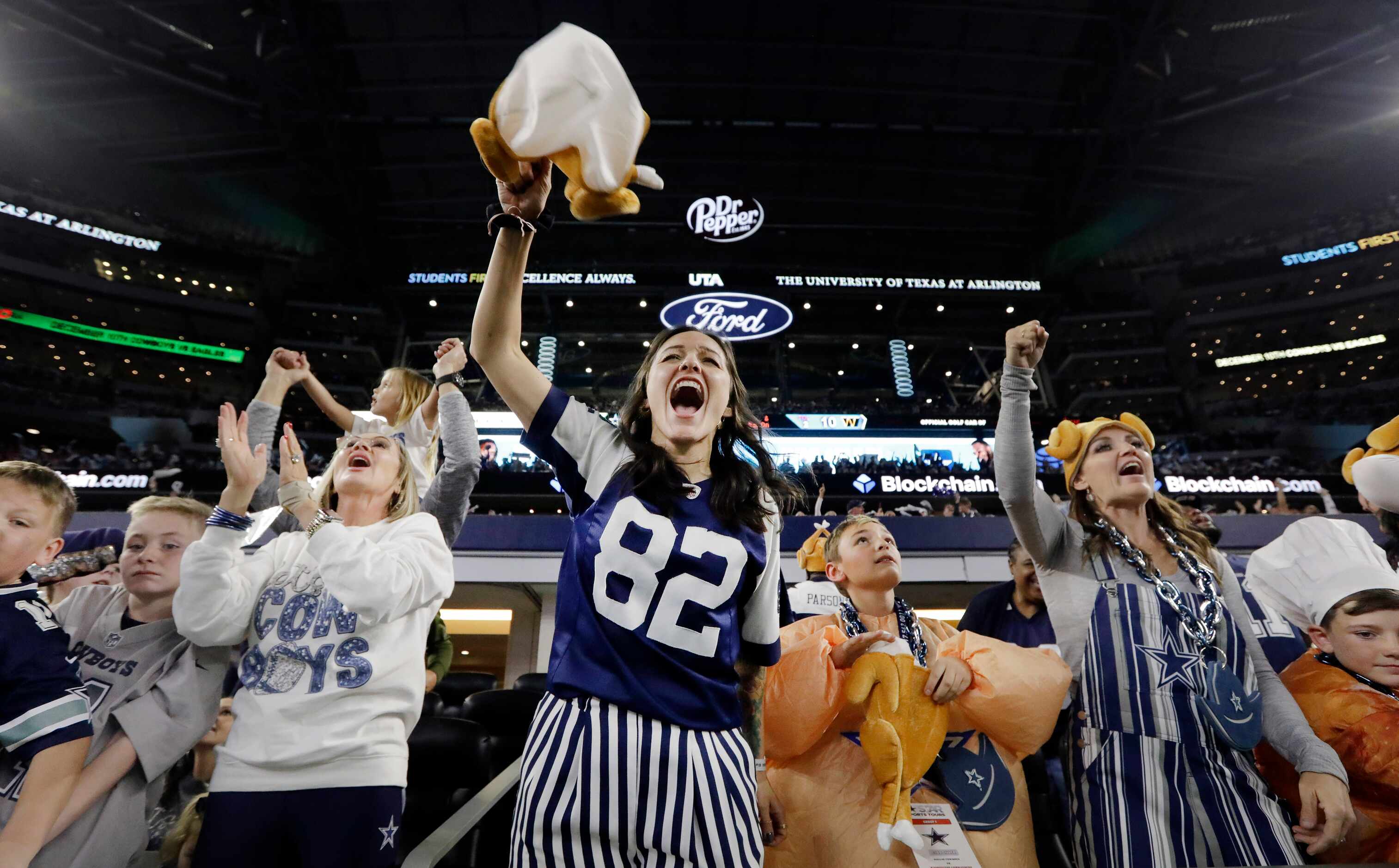Dallas Cowboys fans, some dressed in Thanksgiving attire, cheer for their team against the...