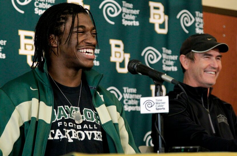 Heisman Trophy winner Robert Griffin III, left, laughs as he and head coach Art Briles...