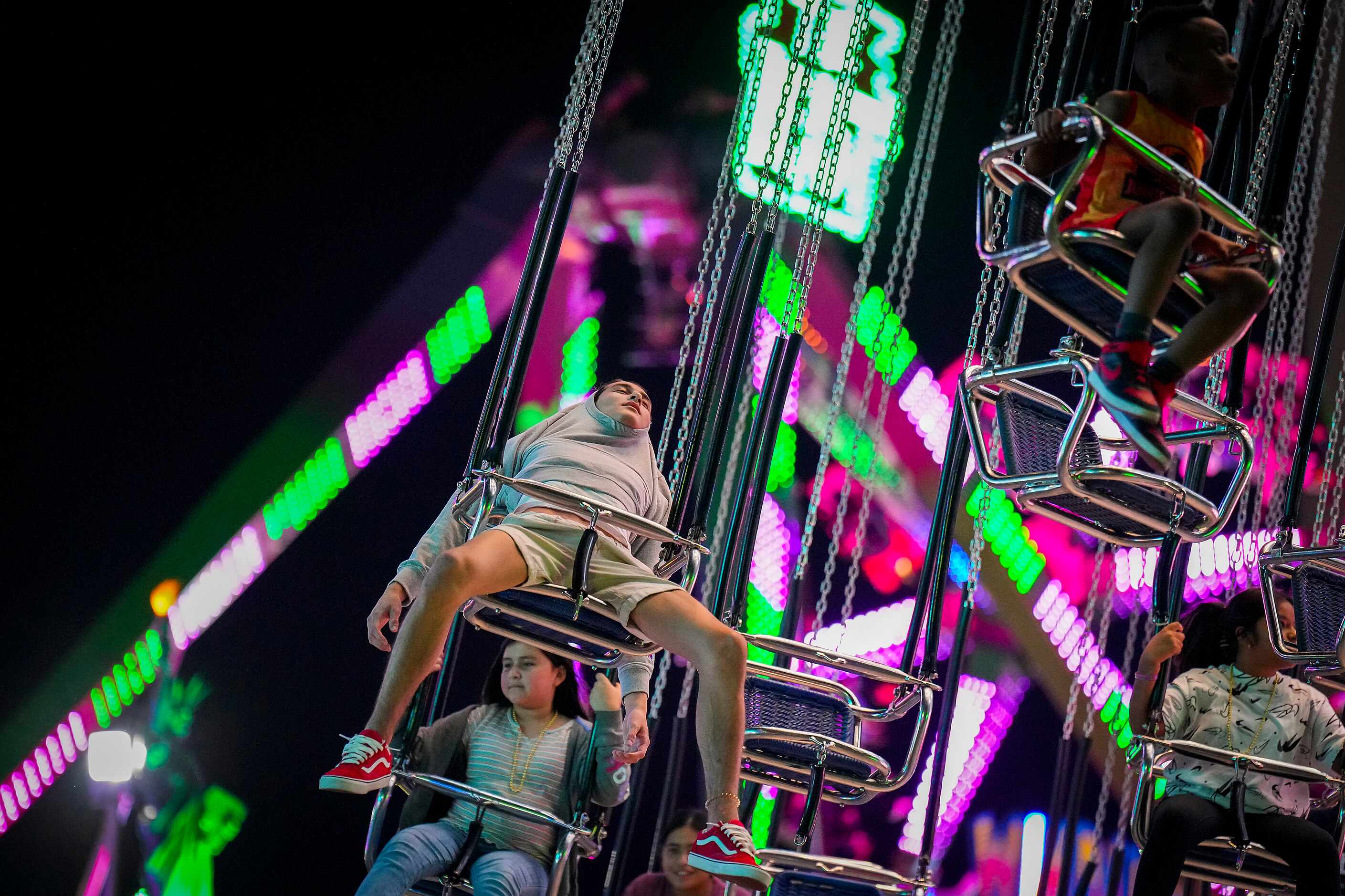Fairgoers spin through the night sky on opening night at the State Fair of Texas on Friday,...