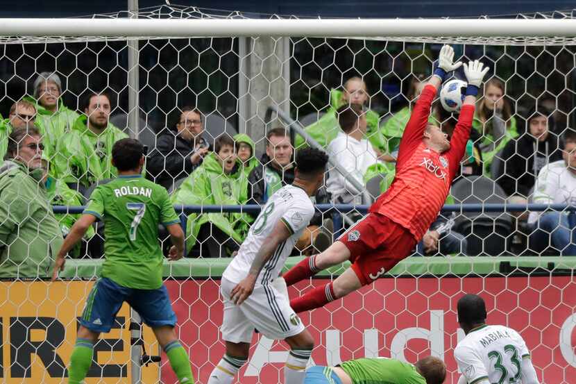 Seattle Sounders goalkeeper Bryan Meredith, upper right, can't stop a header by Portland...