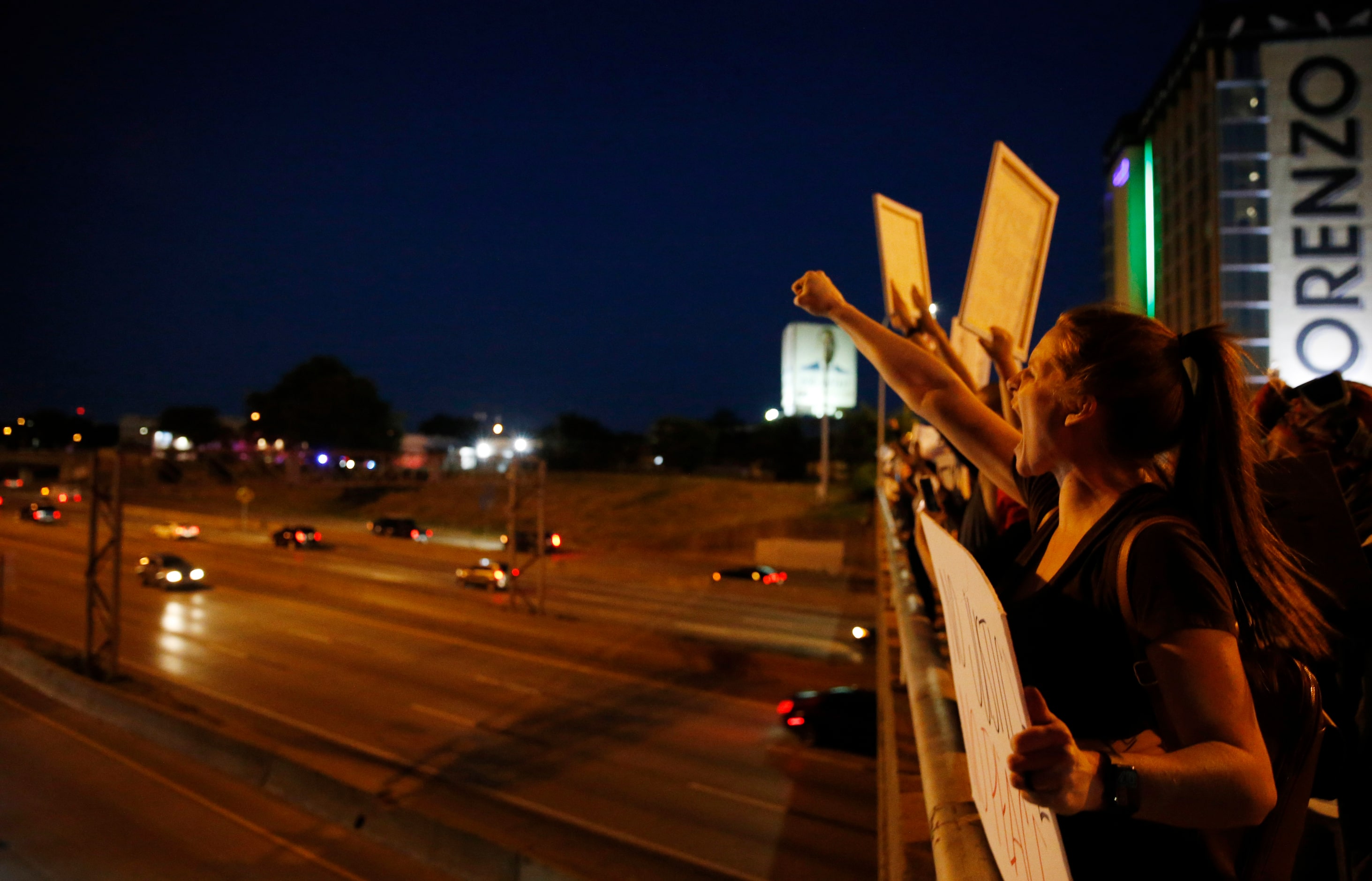 Protesters yell and cheer out on the Akard St. bridge to traffic along Interstate 30 during...