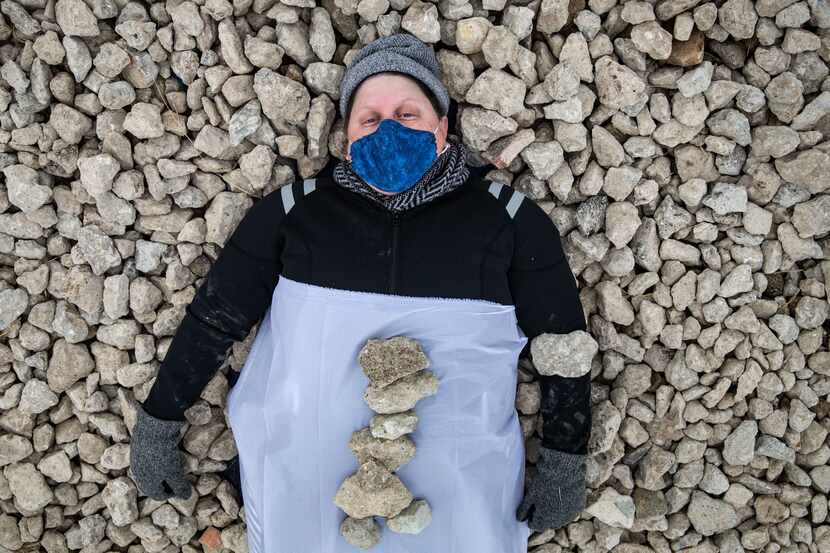 Erica Felicella lays in a bed of stones as she performs “Resistance, Re-Live and Proceed” in...
