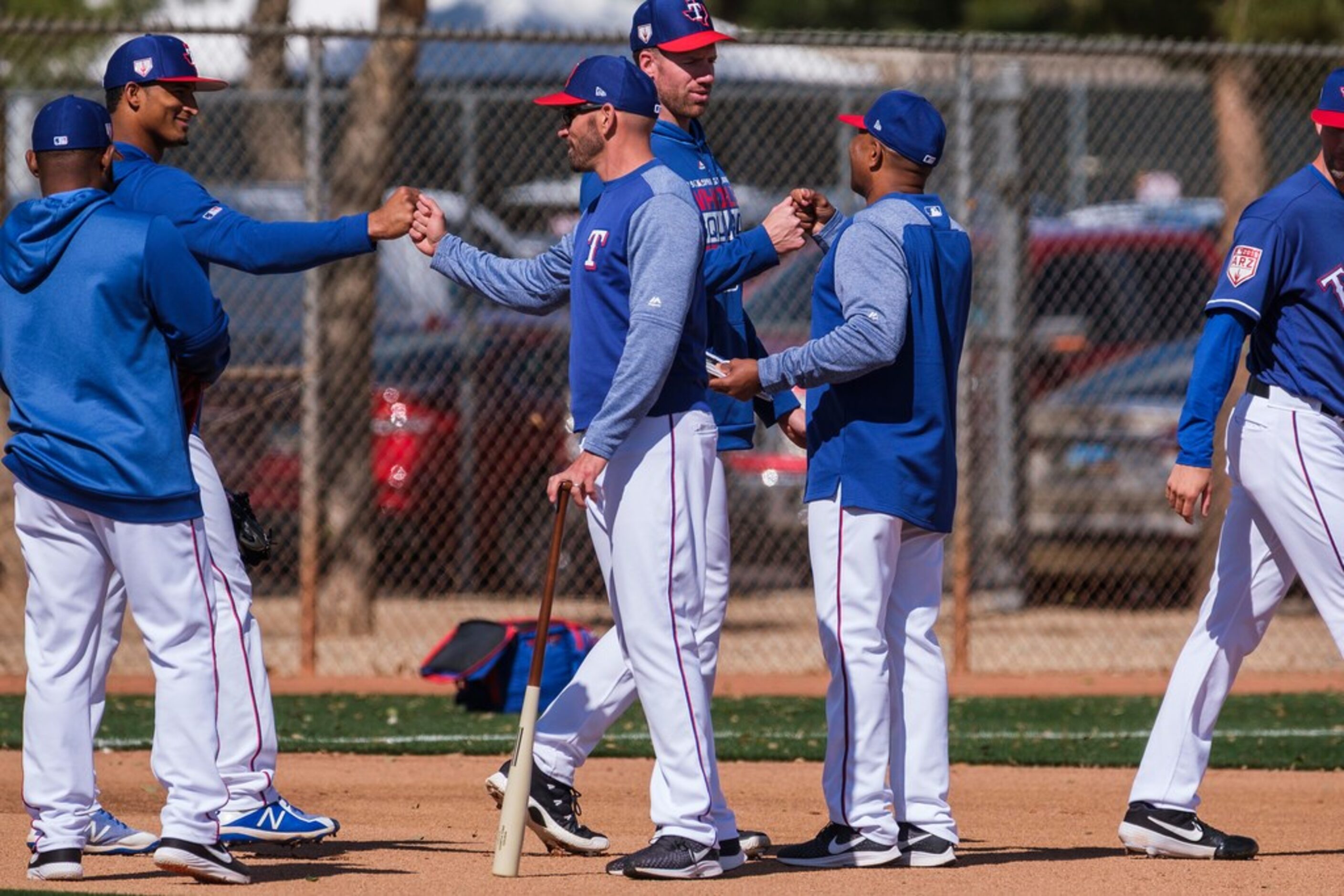 Texas Rangers manager Chris Woodward (center) first bumps pitchers as they head to the...