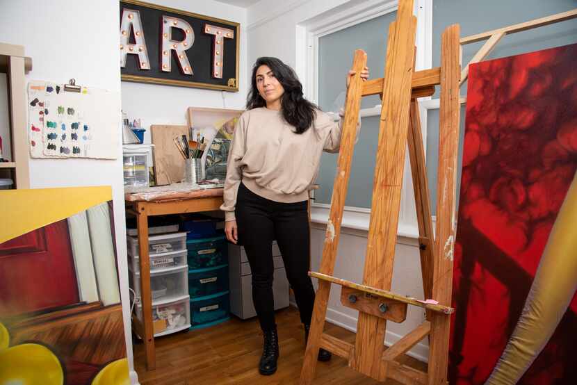 Artist Michelle Cortez Gonzales stands in her studio with her art.
