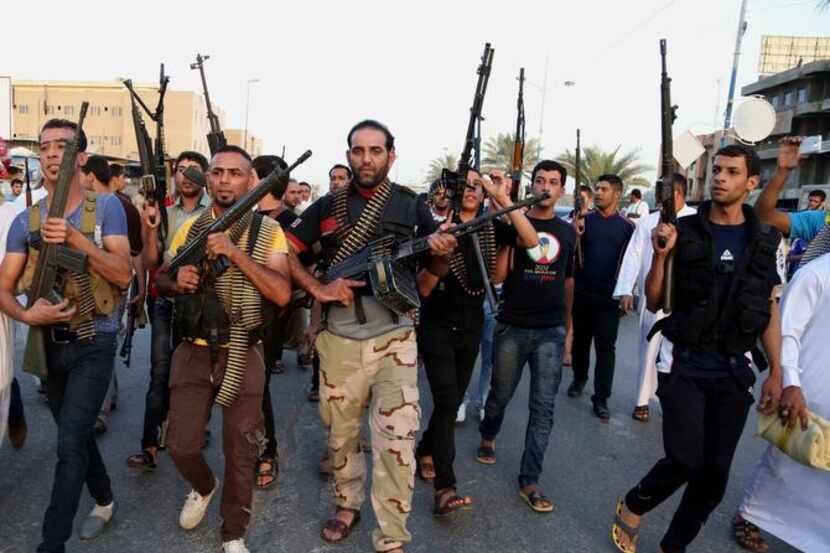 
Iraqi Shiite tribal fighters deploy with their weapons while chanting slogans against the...