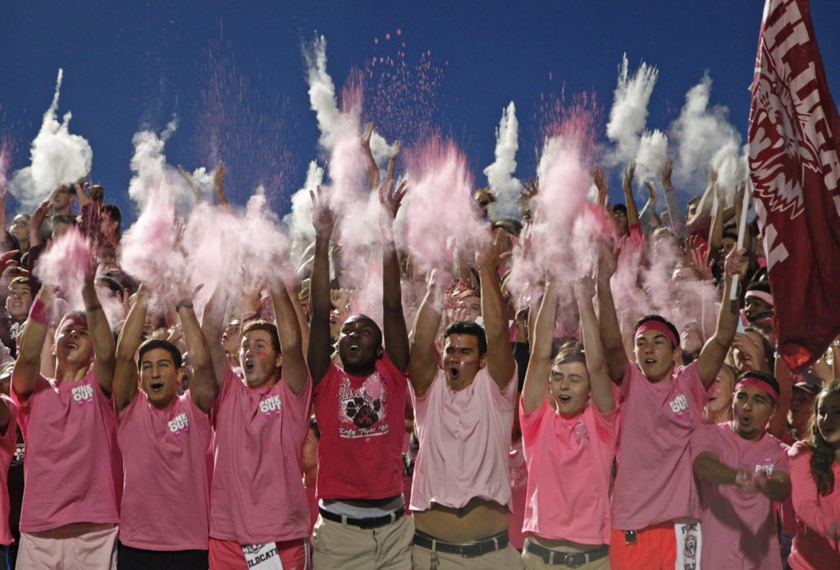 The Plano Senior High School student body dons pink tee shirts as they throw pink colored...