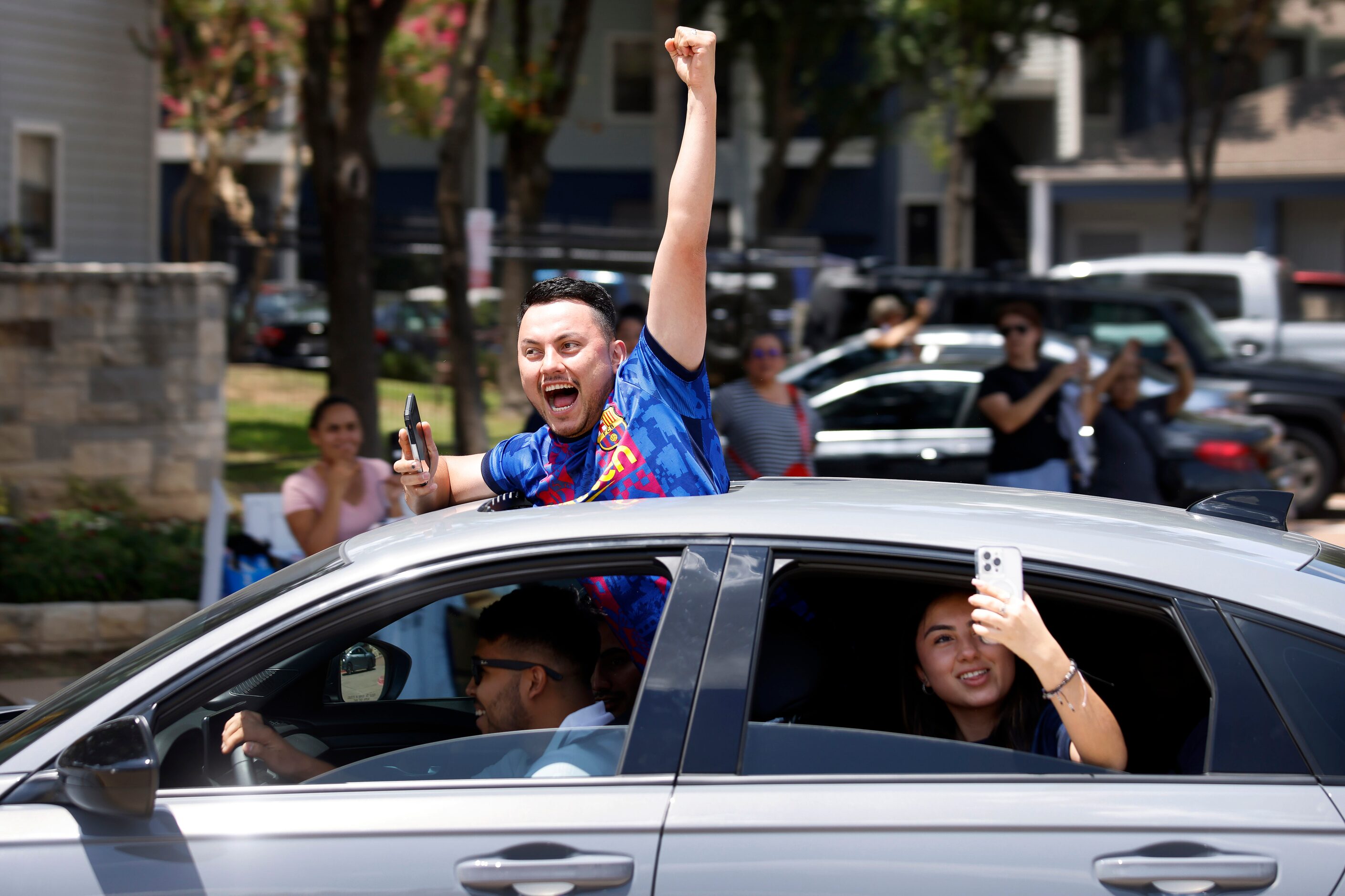 A Barcelona soccer fan cheer s from the sunroof of a passing car before a Soccer Champions...