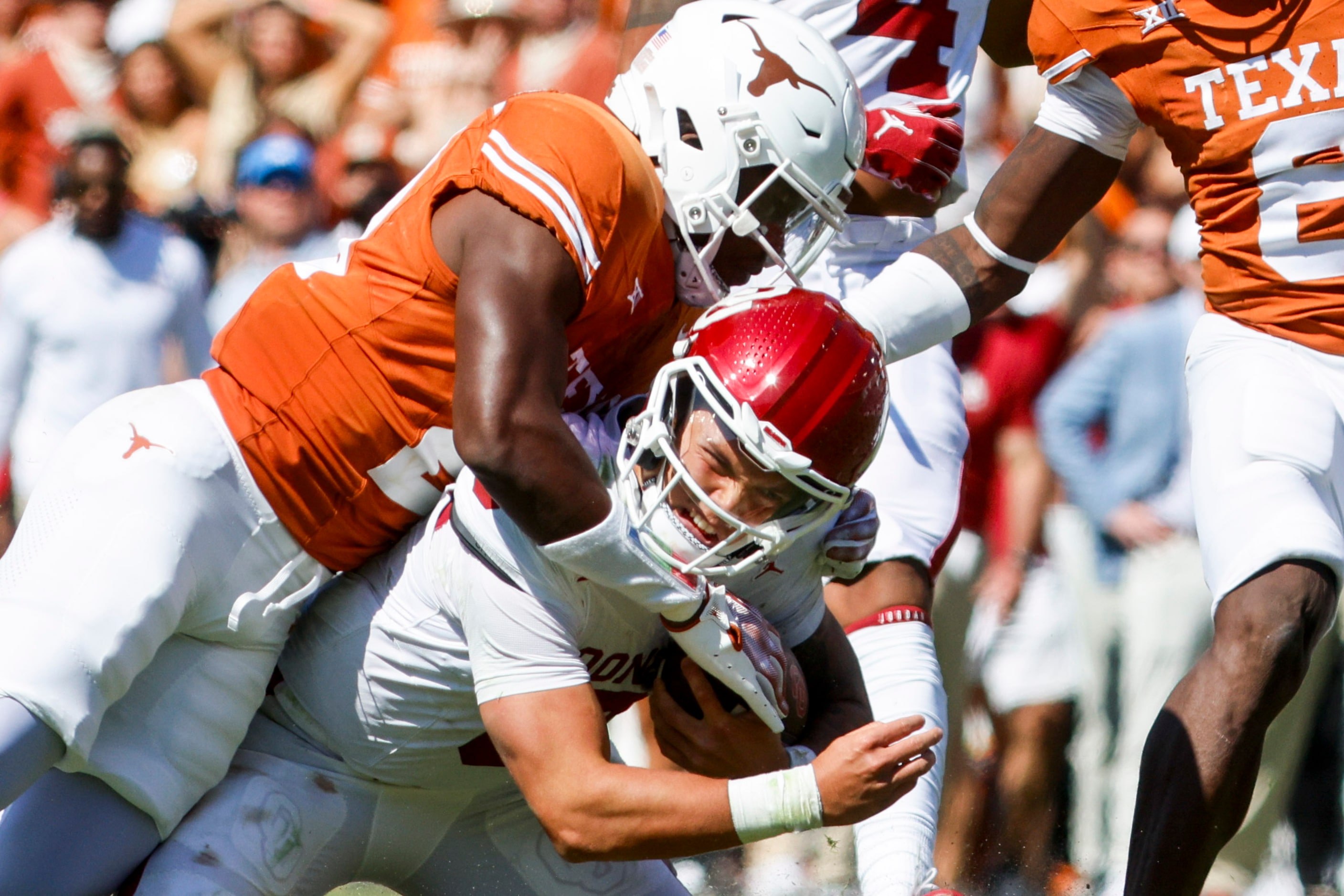 Texas defensive back Kitan Crawford (left) tackles Oklahoma quarterback Dillon Gabriel...