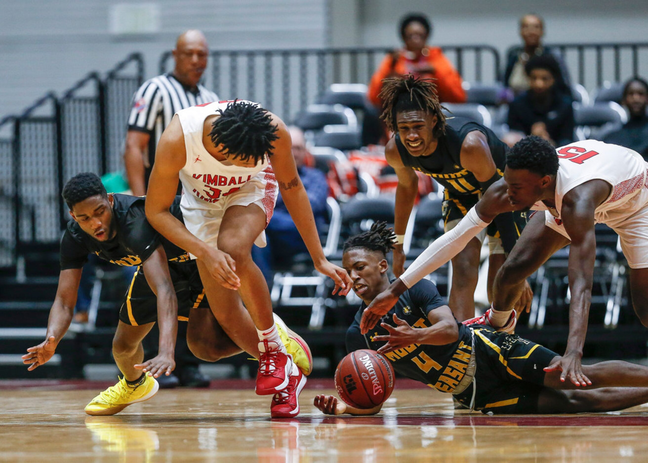 Players grapple to recover a loose ball during the second half of a boys basketball UIL...