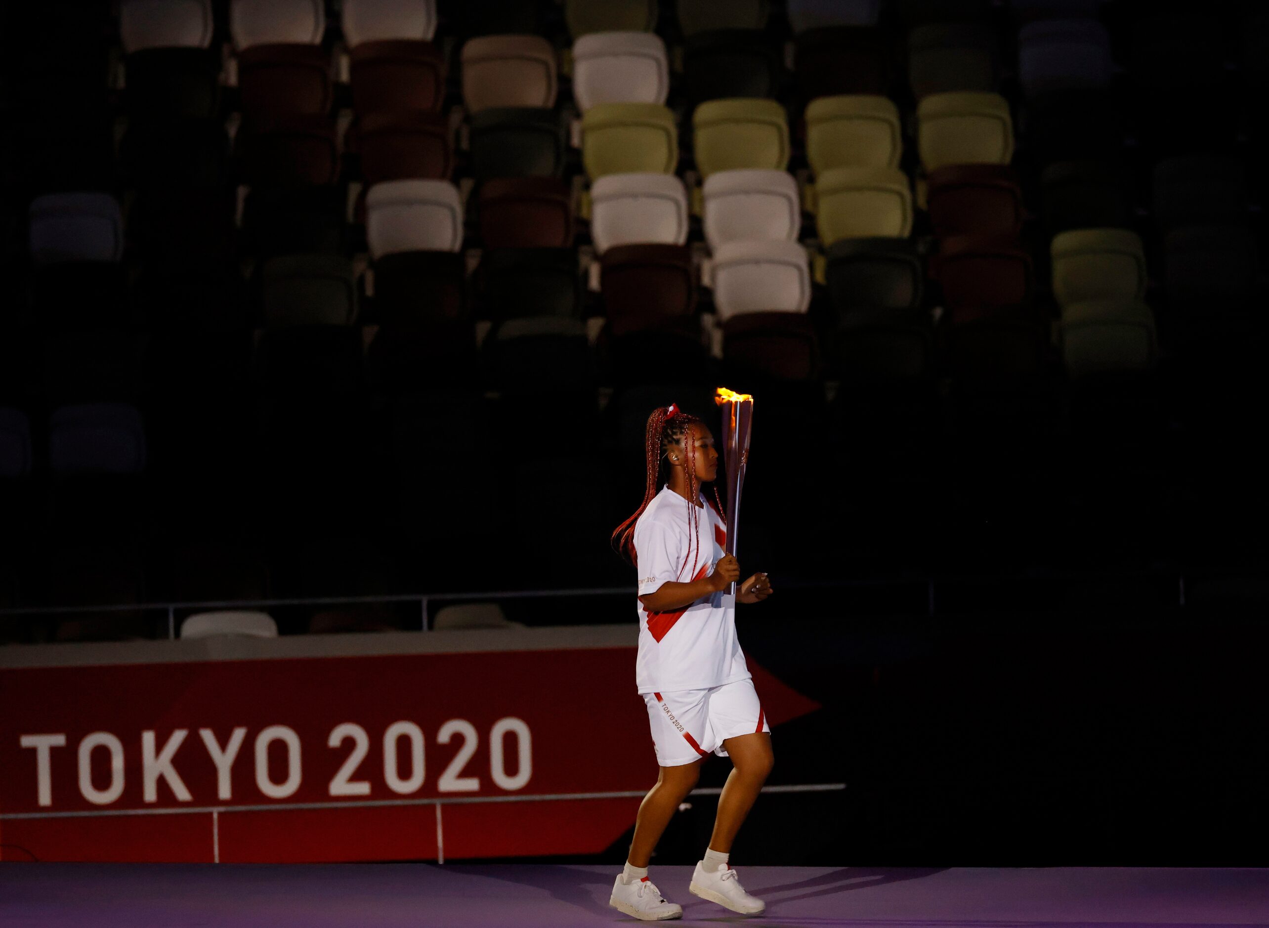 Naomi Osaka carries the Olympic flame during the opening ceremony for the postponed 2020...