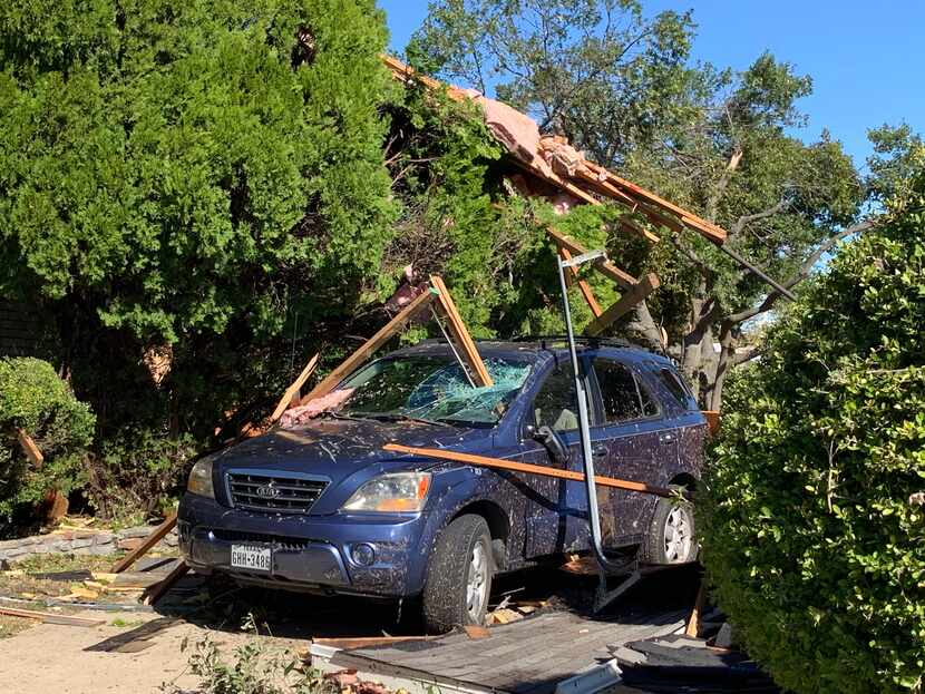 Debris from a nearby house dangles from a tree over a blue Kia SUV in the 1100 block of...