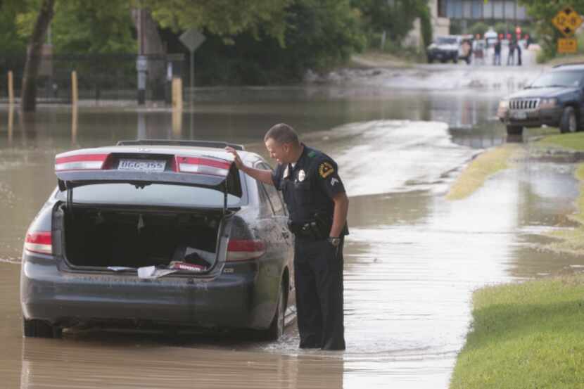 Officer L. Taylor of the Dallas Police waded into a flooded street near White Rock Lake on...