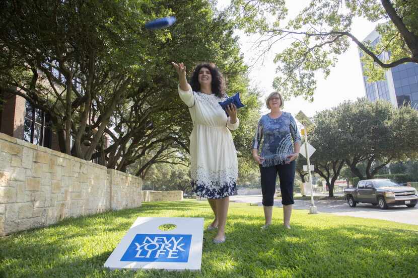 April Abbott, a New York Life agent, throws a beanbag as she plays a beanbag toss with Robin...