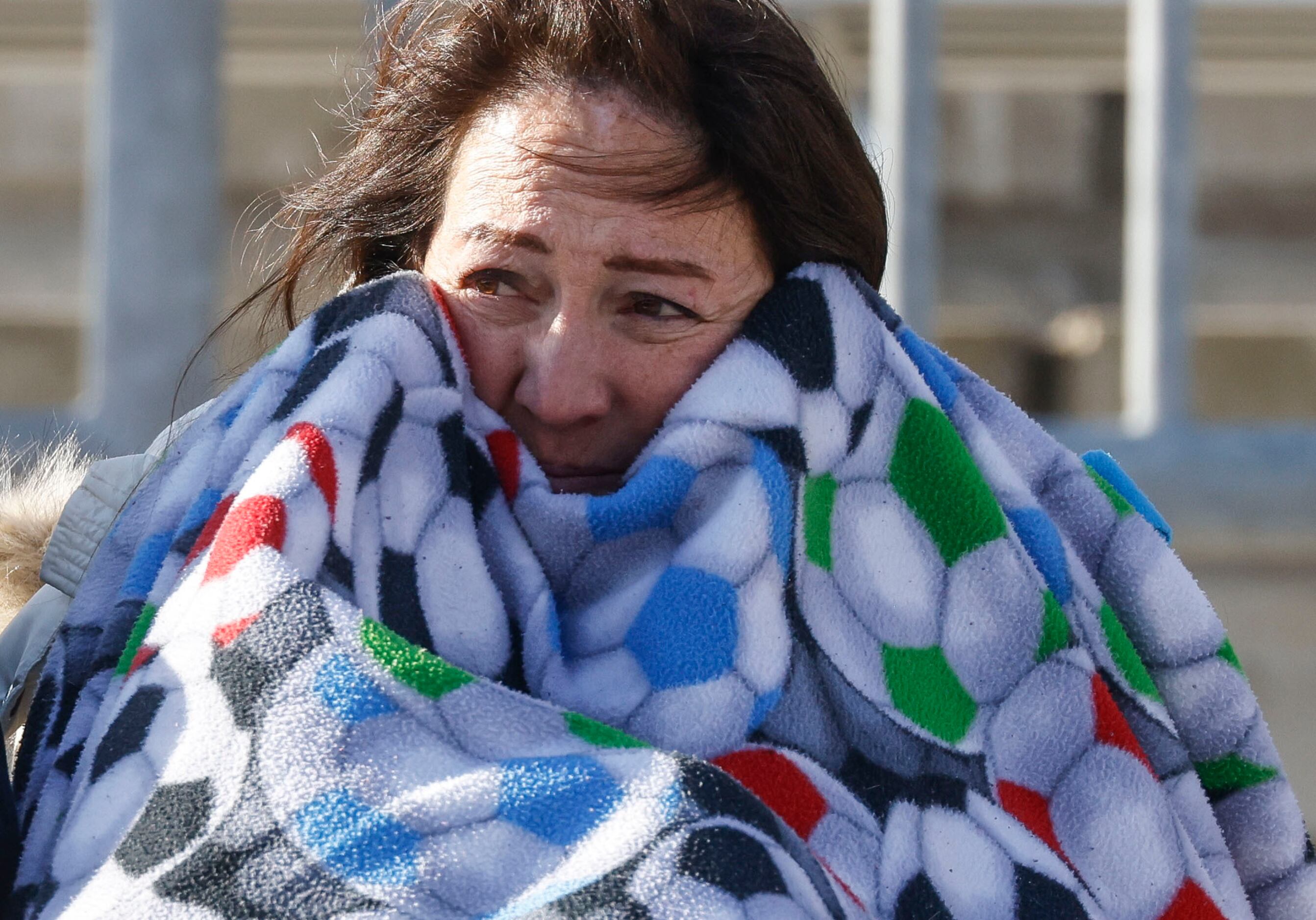 A spectator covers herself from the cold as she watches a soccer game between South Grand...