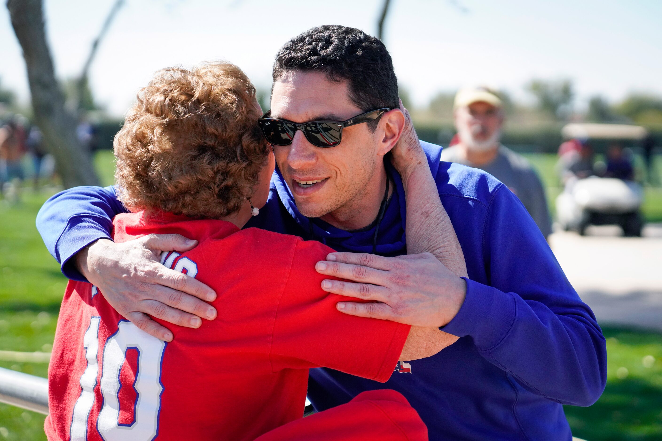 Texas Rangers general manager Jon Daniels hugs fan Shirly Kost following a spring training...