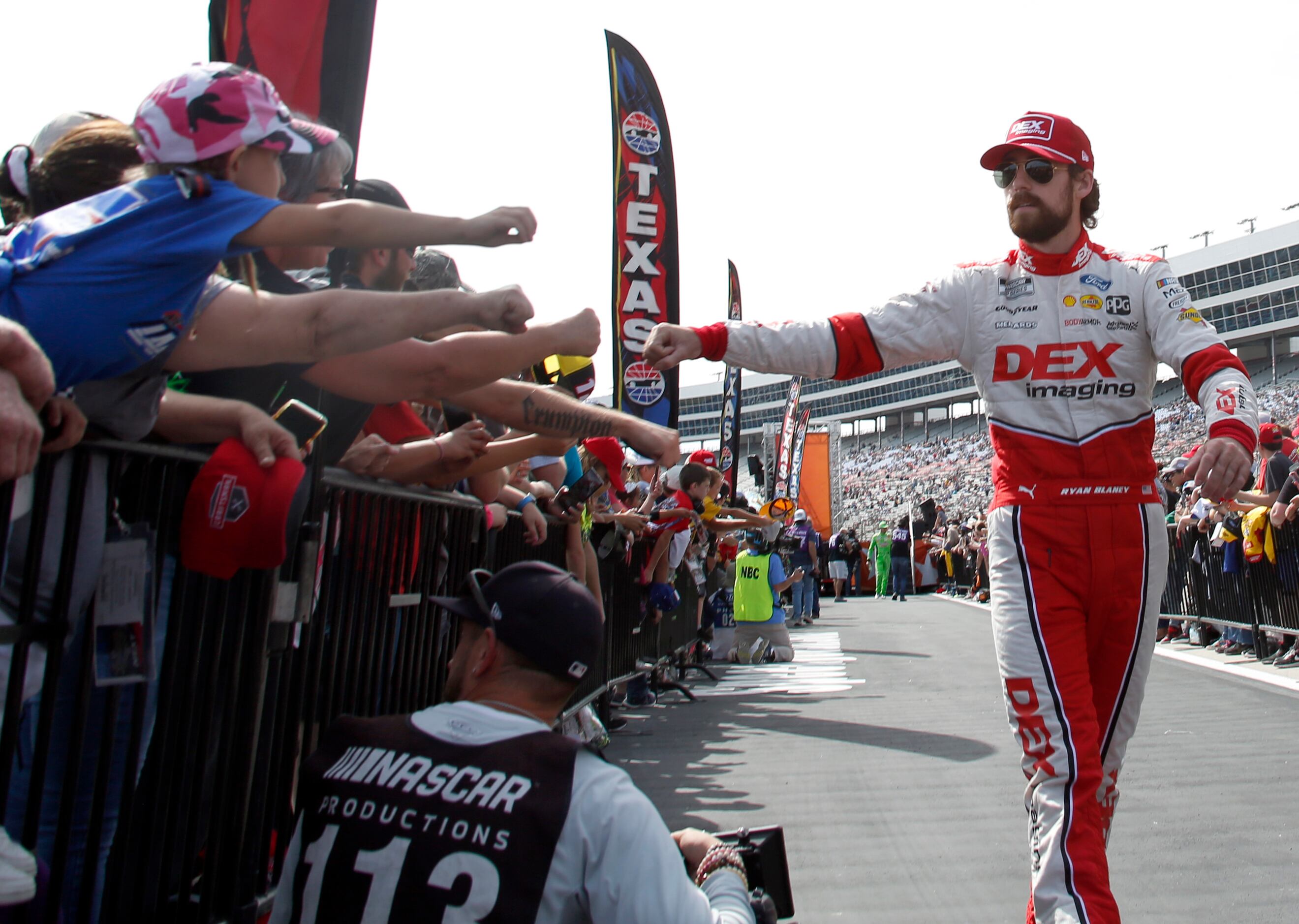 Ryan Blaney, driver of the number 12 Ford car exchanges fist bumps with fans during driver...