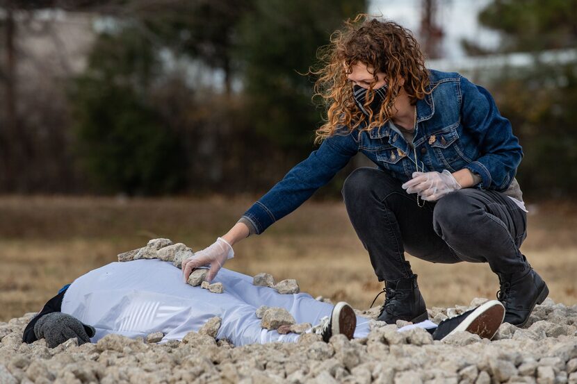 Rachel Stanfield places a stone on artist Erica Felicella.