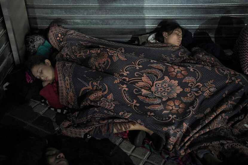 Salvadoran migrants rest at night before joining the caravan heading to the US in San...