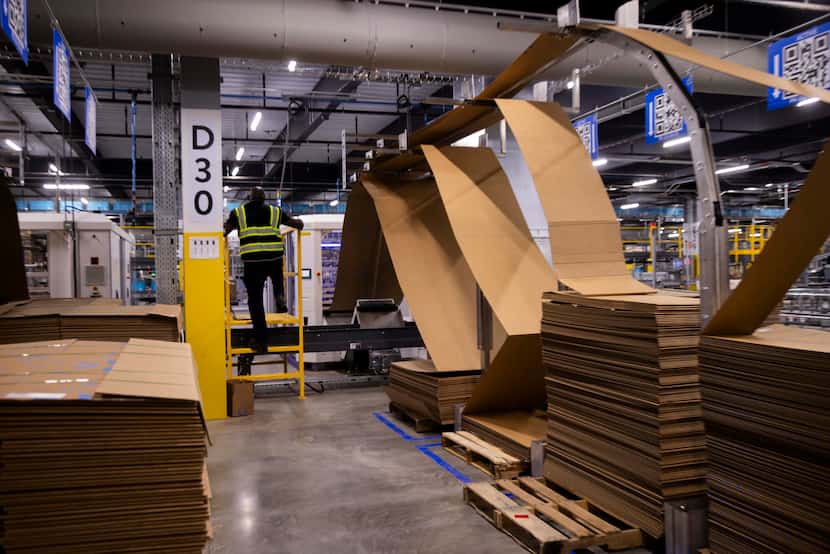 Stacks of cardboard sit behind the box making machine inside of Walmart’s online fulfillment...