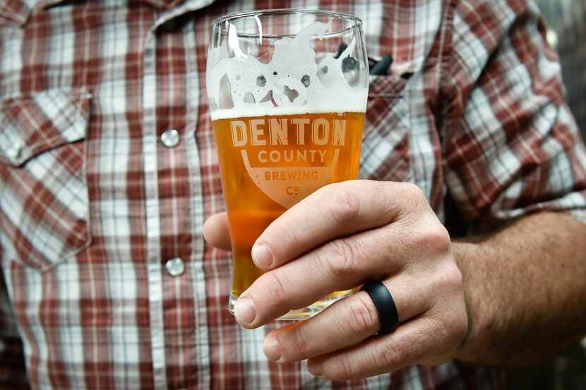 Owner Seth Morgan holds a cold beer at Denton Brewing Co.  Owners are Jenny and Seth Morgan...
