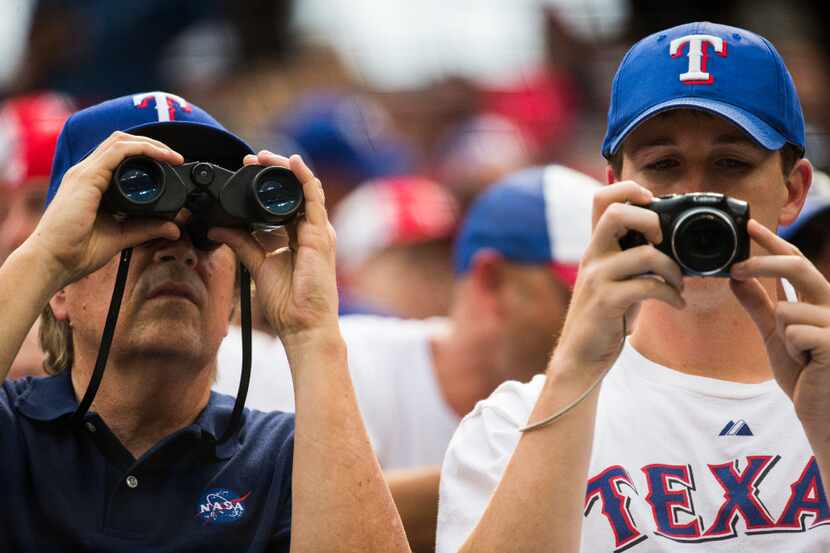 Texas Rangers fans look through binoculars and a camera before an MLB game between the Texas...