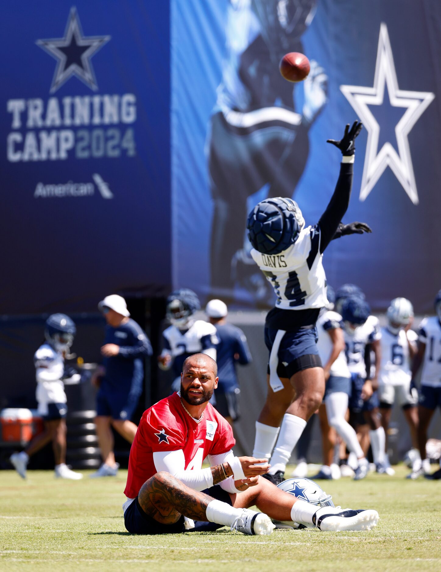 Dallas Cowboys quarterback Dak Prescott (4) stretches as running back Malik Davis (34) leaps...