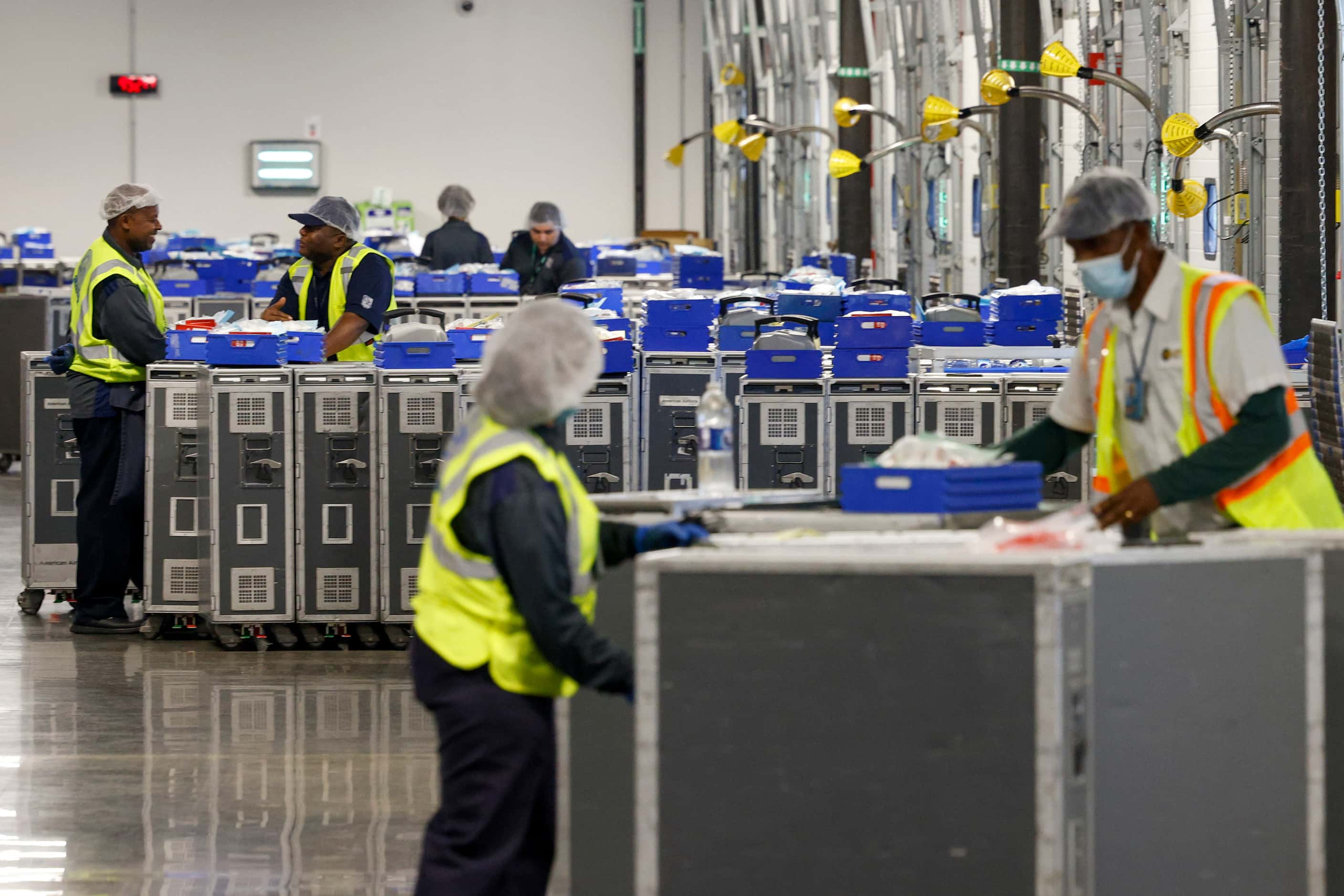 LSG Sky Chefs workers work to load dozens of food and beverage carts onto trucks to be...