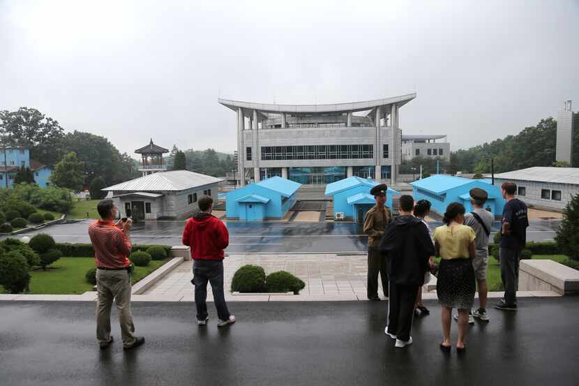Visitors look toward the South Korean building as North Korean soldiers guard the truce...