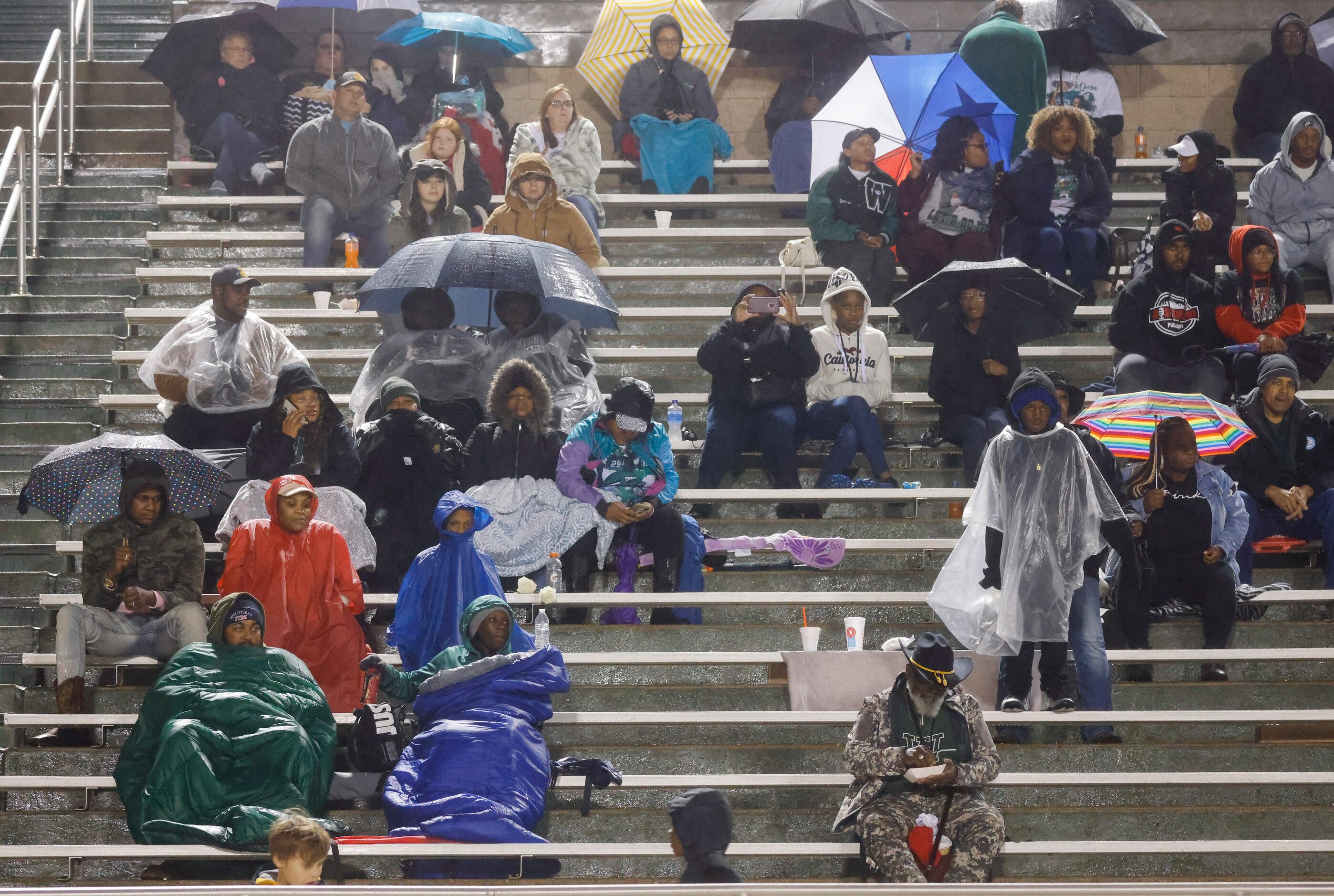 Crowd packed against cold and rain watch a football game between Mansfield Lake Ridge and...