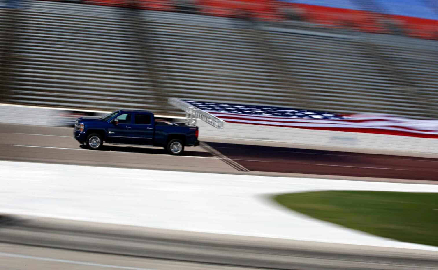 A 2017 Chevrolet Silverado HD hauls an American flag around the track at Texas Motor...
