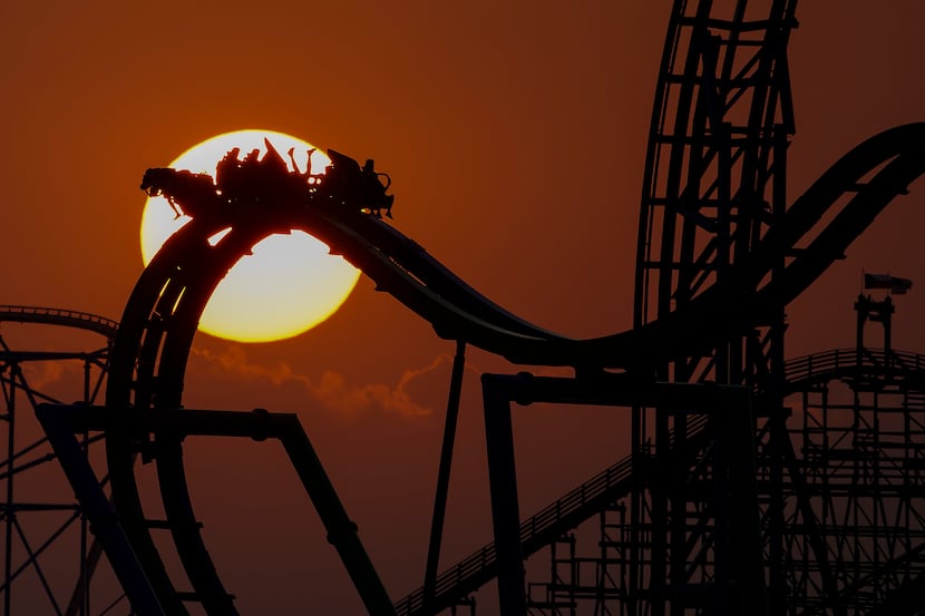 Parkgoers ride The Joker thrill ride as the sun sets behind Six Flags Over Texas amusement...