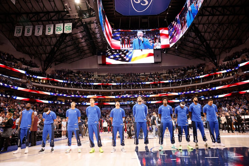 Dallas Mavericks players stand for the national anthem before an NBA basketball game against...