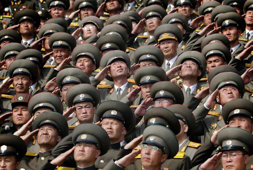 North Korean soldiers salute as their national anthem is played during a military parade to...