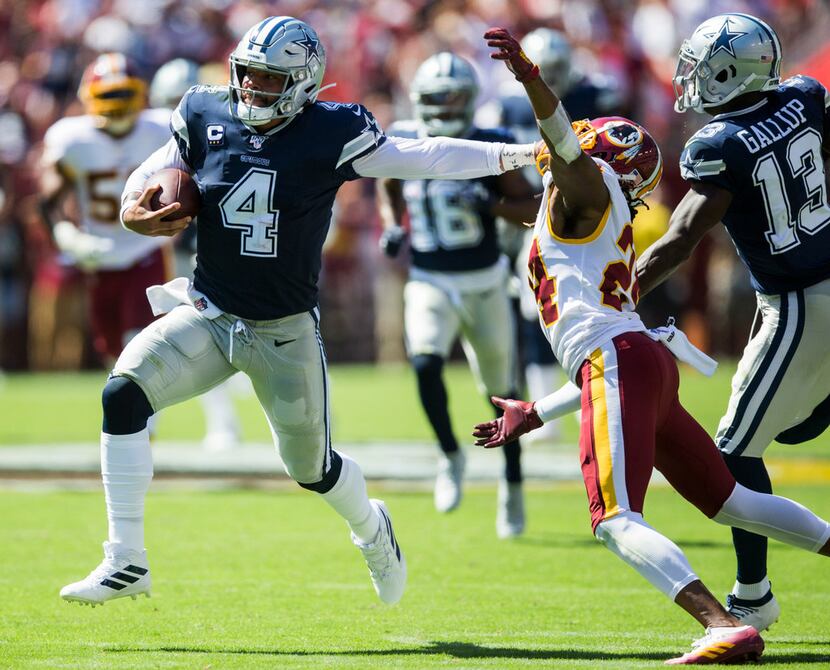 Dallas Cowboys quarterback Dak Prescott (4) stiff arms Washington Redskins cornerback Josh...