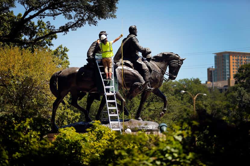 A crewman from Howell Crane and Rigging, Inc measures the height of the Robert E. Lee statue...