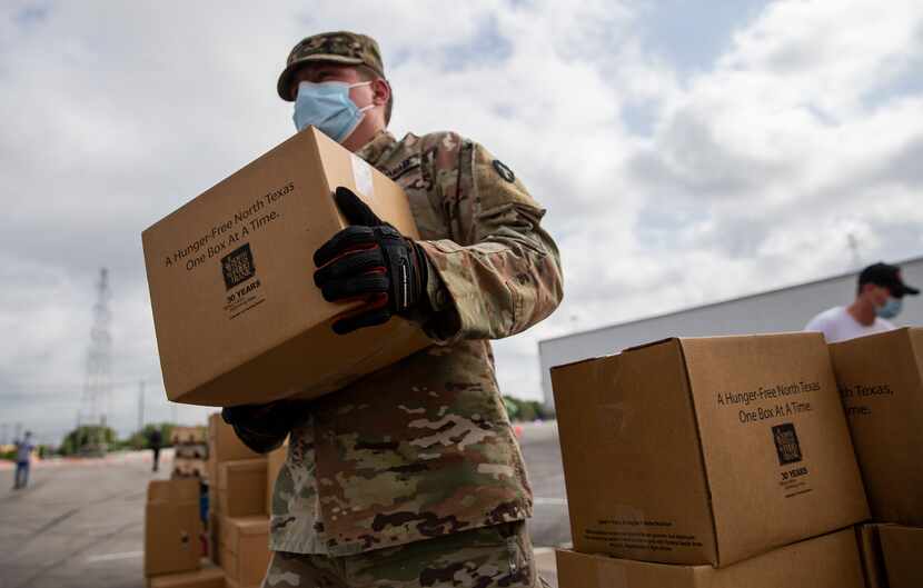 A member of the Texas National Guard waits to load a car while helping with the food...