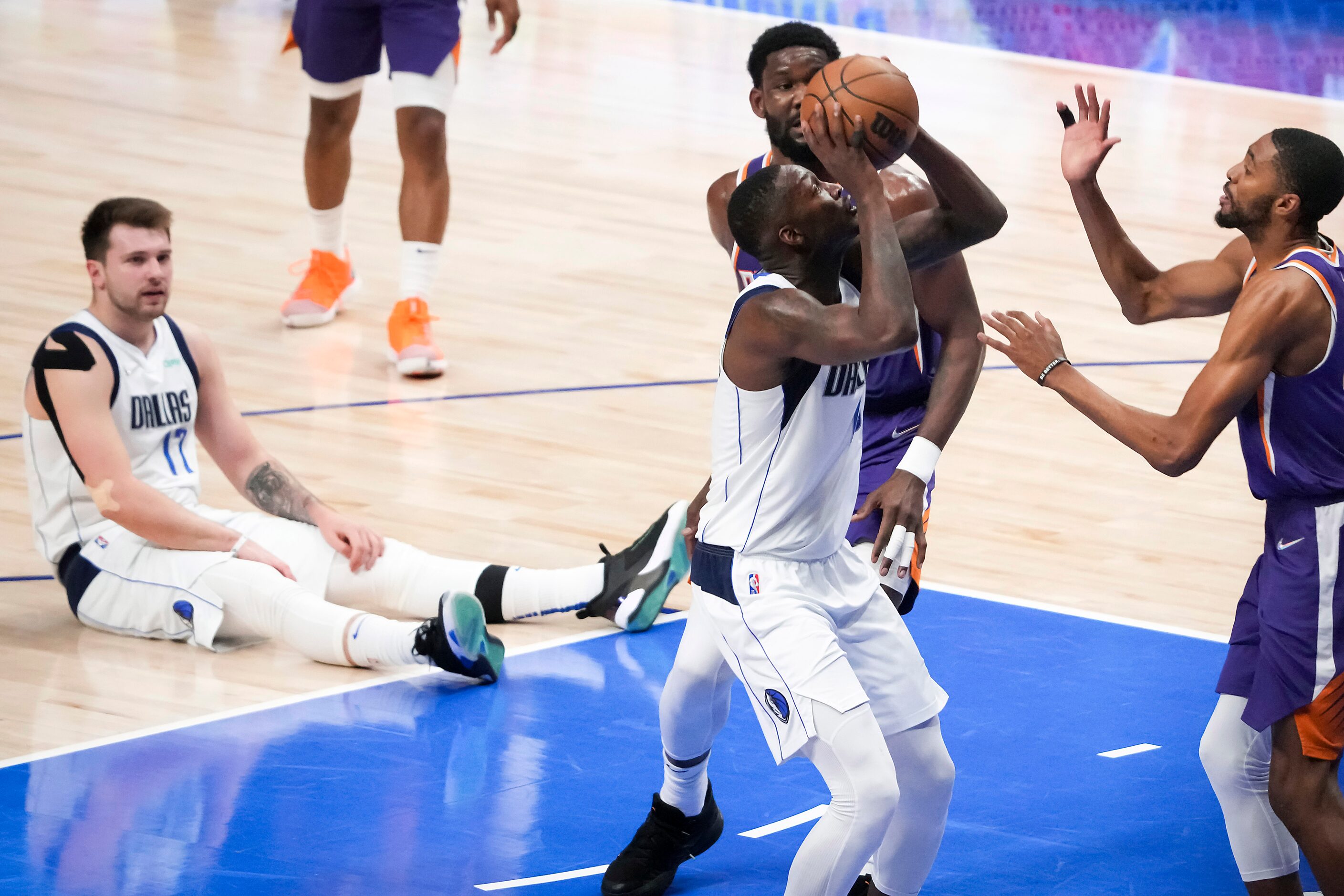 Dallas Mavericks forward Dorian Finney-Smith drives to the basket as guard Luka Doncic sits...