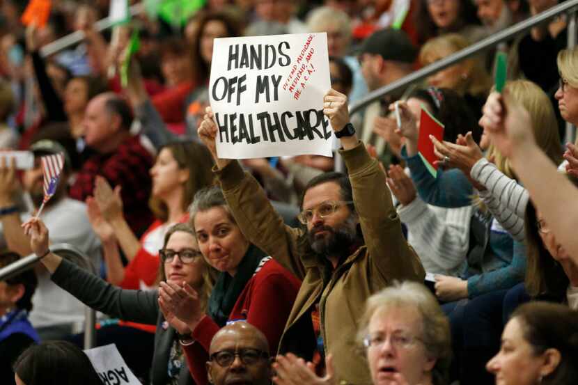 People cheer after a question about the Affordable Care Act during a town hall meeting with...