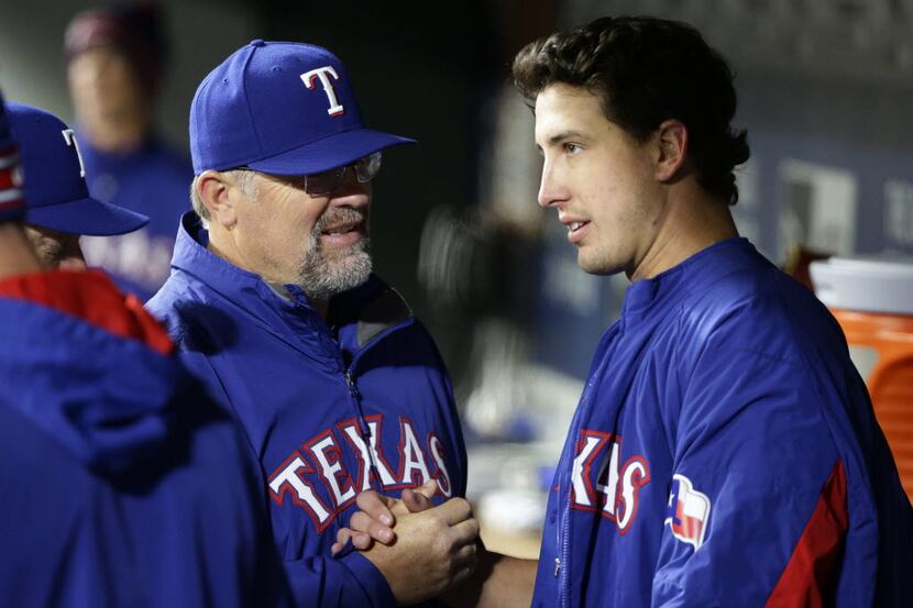 Texas Rangers pitching coach Doug Brocail, left, talks with starting pitcher Derek Holland...