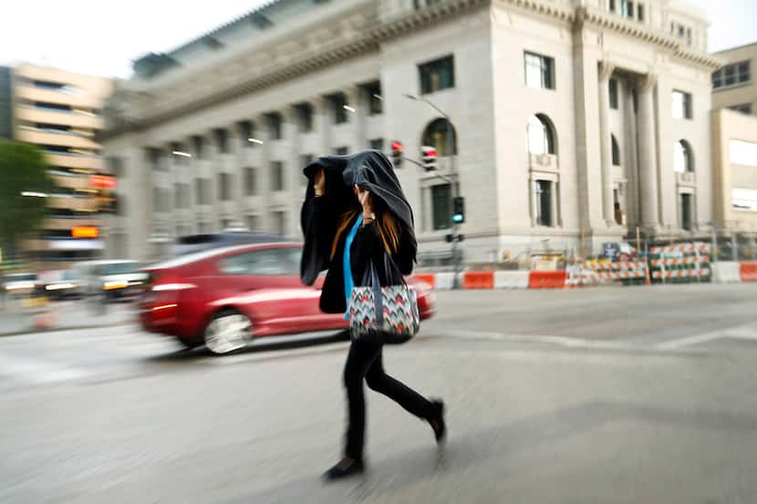 A woman takes cover from a passing shower in downtown Dallas on Tuesday, after a...