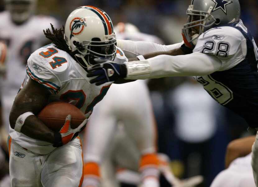 Miami RB Ricky Willliams (34) stiff arms Dallas S Darren Woodson in the third quarter as the...