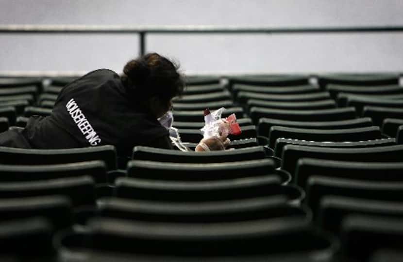  Mirella Santoyo cleans trash from audience seating areas at Reunion Arena after the Plano...