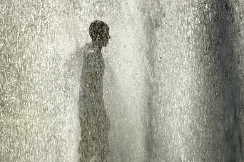 A man stands in a fountain to cool off as the temperature hit 102 degrees Thursday, June 28,...