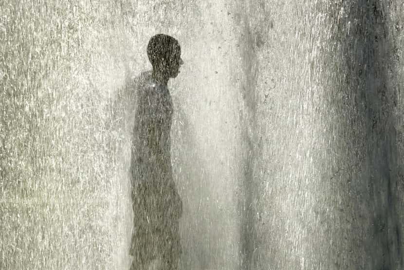 A man stands in a fountain to cool off as the temperature hit 102 degrees Thursday, June 28,...