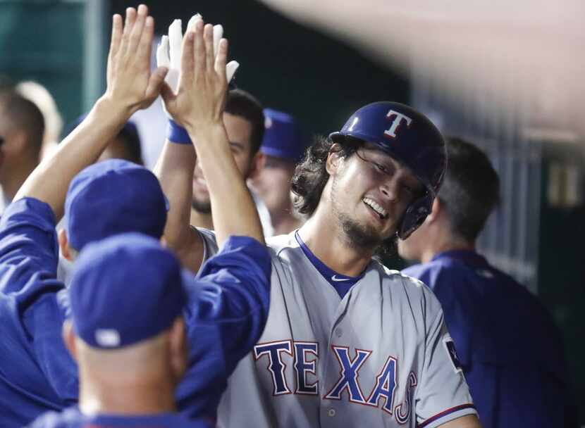 Texas Rangers' Yu Darvish rcelebrates in the dugout after hitting a solo home run off...