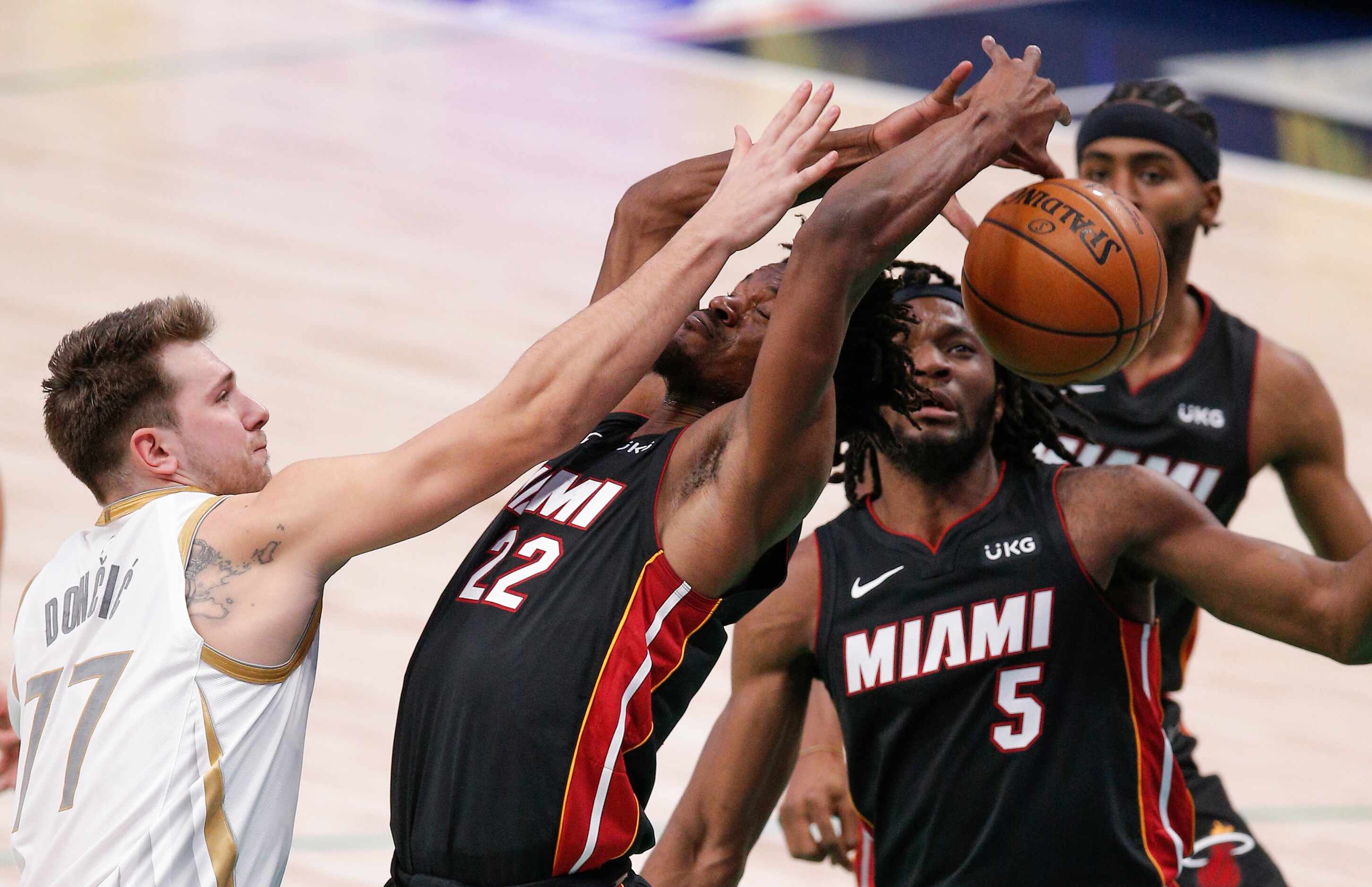 Dallas Mavericks guard Luka Doncic (77) battles Miami Heat forwards Jimmy Butler (22) and...