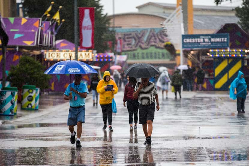 Fairgoers walk through the rain on the Midway at the State Fair of Texas. 