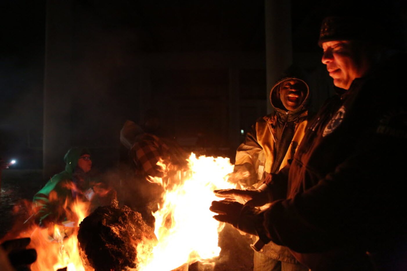 James Allen (left) warms his hands with Dallas police Officer Everard Wortham (right) during...